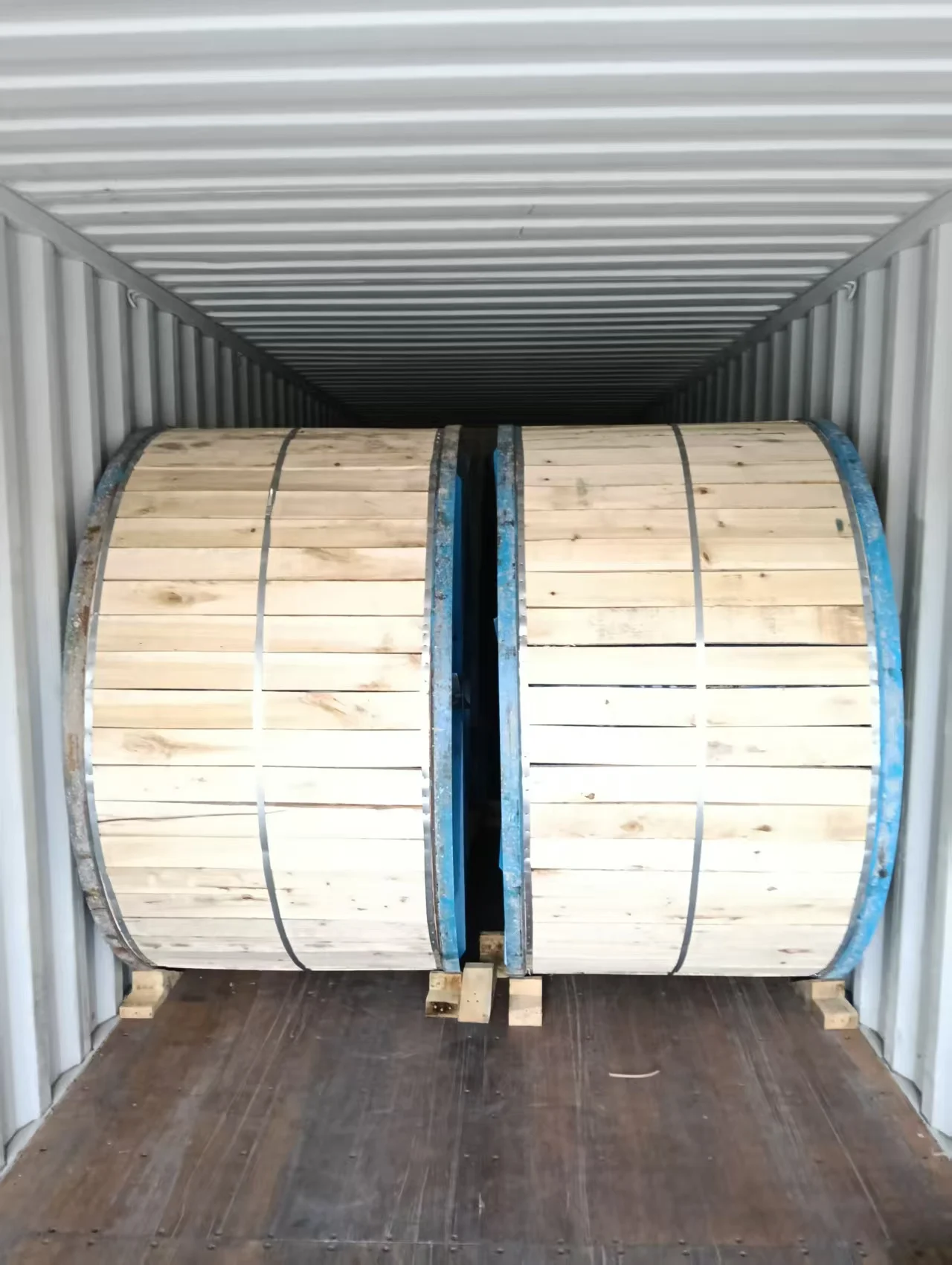 large wooden ABC cable drums securely packed inside a shipping container for international transport or export